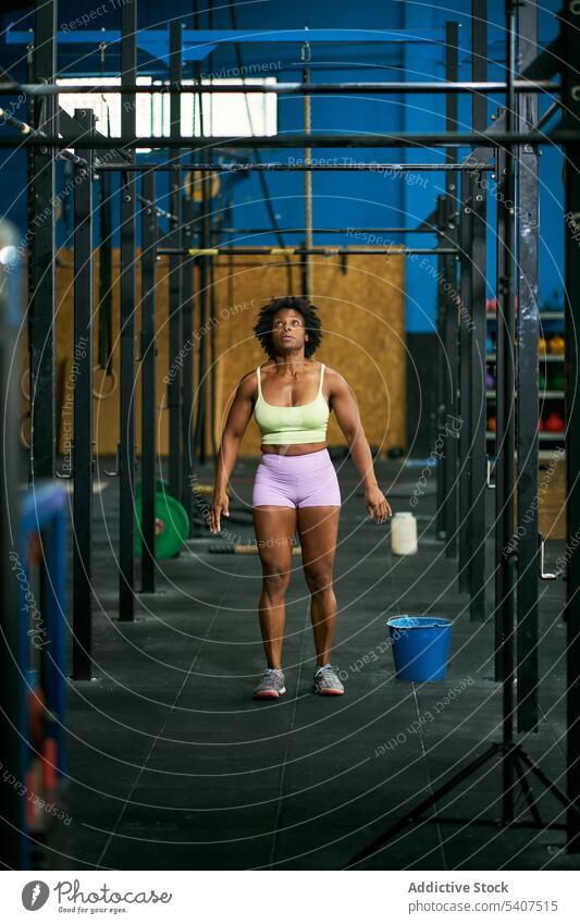 Fitte schwarze Sportlerin, die in einem Fitnessstudio auf dem Affenbarren trainiert Übung Affenstange Training stark muskulös Herausforderung Gesundheit