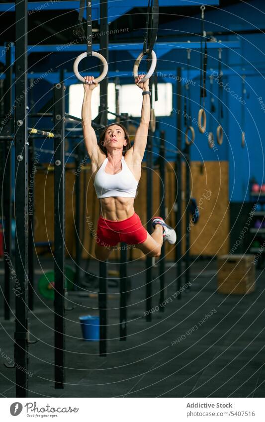 Starke Sportlerin beim Hochziehen an den Turnringen Übung hängen Ring Training muskulös Herausforderung Ausdauer Frau Erwachsener Fitness physisch