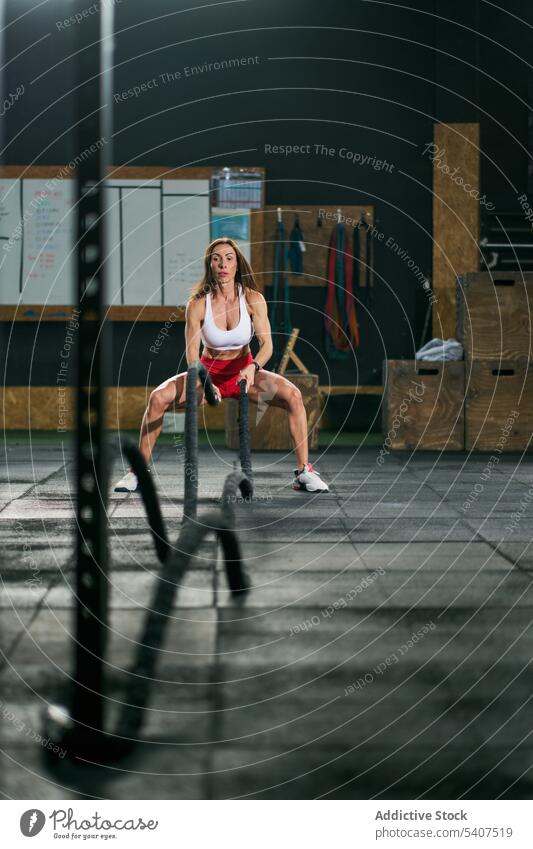Starke Sportlerin beim Training mit Kampfseilen Schlacht Seil Übung Körper anstrengen stark muskulös Fitnessstudio Frau Erwachsener Stärke Ausdauer operativ