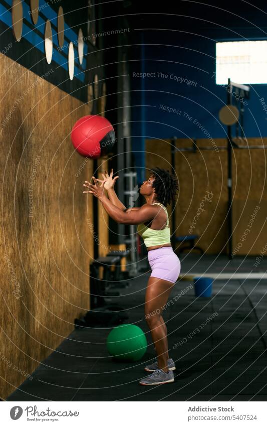 Starke schwarze Sportlerin wirft Medizinball gegen die Wand werfen Ball Übung Kraft Gewicht Training Fitnessstudio Frau reif Afroamerikaner ethnisch Afro-Look