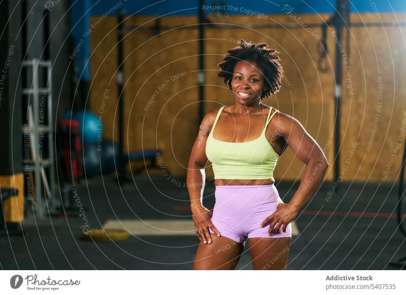 Glückliche schwarze reife Sportlerin mit Afrofrisur selbstbewusst Training stark muskulös Fitness Fitnessstudio Gesunder Lebensstil Wellness emotionslos Frau