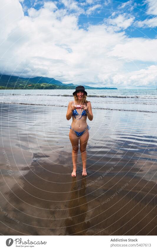 Lächelnde Frau am Meeresufer mit Retro-Kamera Resort Filmmaterial retro Fotoapparat Strand MEER Ufer Sommer winken heiter jung uvita Puntarenas Costa Rica