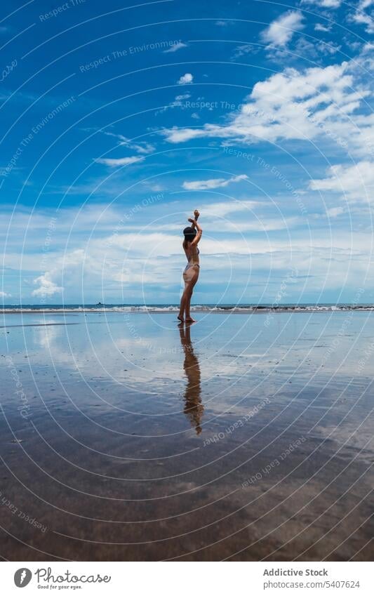Frau steht am nassen Strand vor blauem Himmel mit Wolken winken MEER Meer Resort reflektieren Arme hochgezogen Sand Ufer sorgenfrei jung uvita Puntarenas