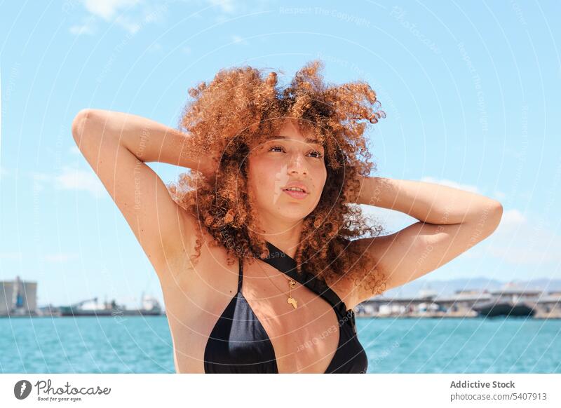 Unbekümmerte ethnische Frau vor blauem Himmel genießen Sommer Sonne sorgenfrei Bikini Top Inhalt sich[Akk] entspannen Afro-Look Frisur Urlaub schlank Shorts