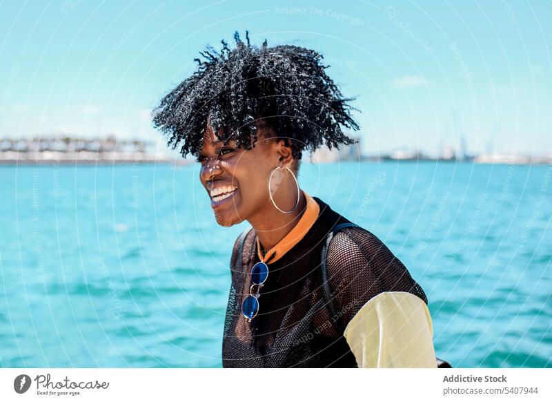 Charmante schwarze Frau auf dem Deich in der Stadt Strandpromenade Hafengebiet genießen sich[Akk] entspannen sonnig Afro-Look Frisur charmant Lächeln ethnisch