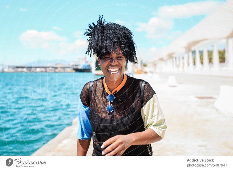 Charmante schwarze Frau auf dem Deich in der Stadt Strandpromenade Hafengebiet genießen sich[Akk] entspannen sonnig Afro-Look Frisur charmant Lächeln ethnisch
