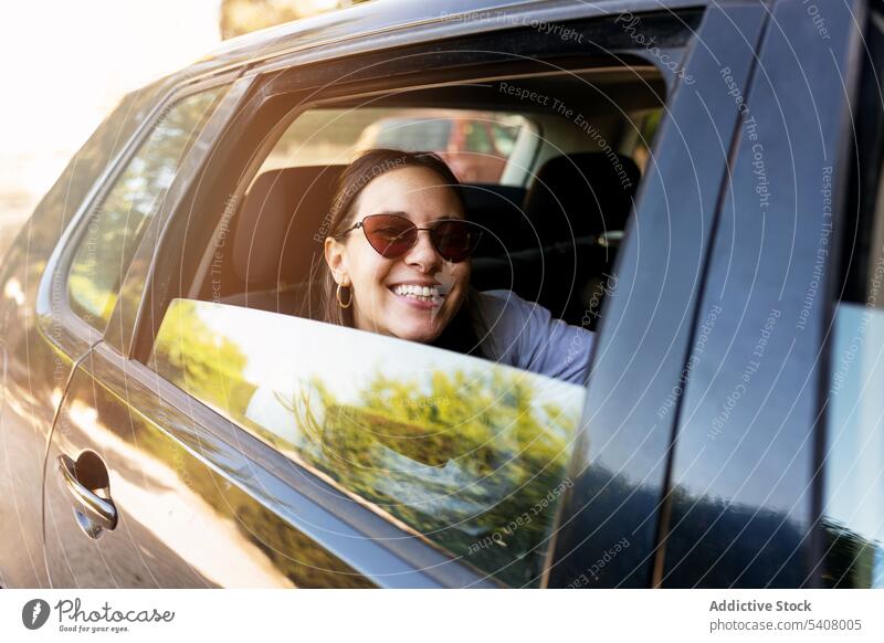 Zufriedene Frau sitzt im Auto und schaut in die Kamera PKW Rücksitz Automobil heiter sich[Akk] entspannen Sitz modern geparkt Großstadt positiv jung trendy