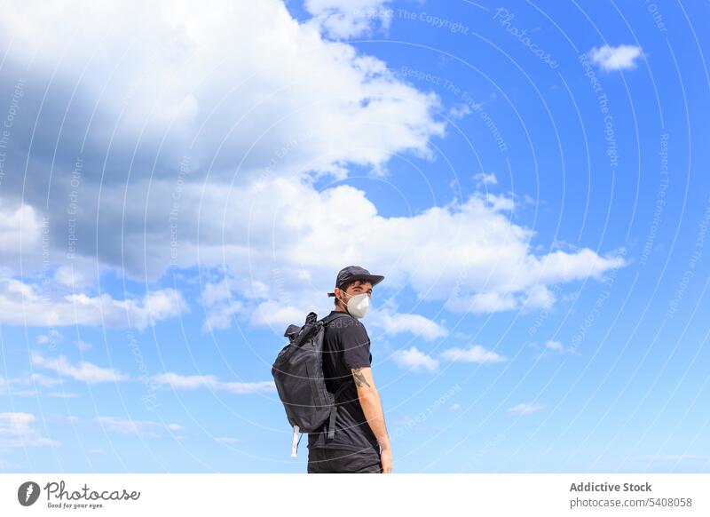 Männlicher Reisender, der während eines Sommerausflugs unter dem Himmel steht Tourist genießen Ausflug Rucksack verträumt Freiheit Mann Natur Blauer Himmel