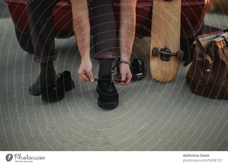 Crop-Skaterin bindet Schnürsenkel und lehnt sich an den Kofferraum eines Autos Mann Skateboard Wandel & Veränderung Krawatte Schuhbänder Turnschuh Hobby
