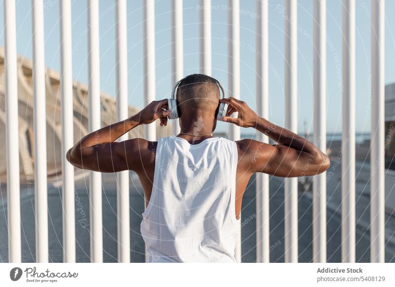 Von hinten schwarzer, sportlicher Mann, der Musik hört Läufer anonym benutzend Kopfhörer zuhören Training Athlet Pause Sportler Apparatur Sportbekleidung