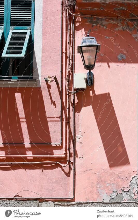 Fensterladen und Lampe werfen Schatten auf rosa Fassade, Stromleitungen teilen das Bild Laterne schräg Italien italienisch Reise reisen Haus Altstadt historisch