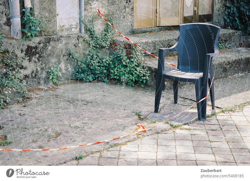 Einsamer Plastikstuhl, rot-weißes Absperrband, verlassene Gegend, verloren Stuhl Stapelstuhl Band nutzlos sinnlos sitzen hinsetzen leer Sitzgelegenheit frei