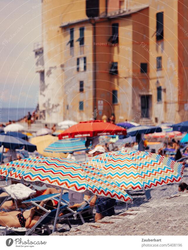 Bunte Sonnenschirme vor ockerfarbenen Häusern am Strand der italienischen Riviera bunt Baden Urlaub Erholung Italien Ferien & Urlaub & Reisen Meer Sommer Sand