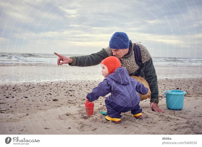 Vater und Kind machen eine Entdeckung am Strand neugierig Kindererziehung zeigen beobachten papa Natur Zusammensein entdecken erkunden begleiten Neugier Sand
