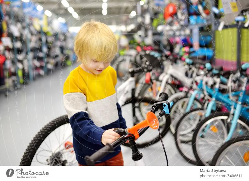 Kleiner Junge sucht sich im Sportgeschäft ein Fahrrad aus. wählte auserwählend Kind Laden Werkstatt Vorschulkind Schutz kaufen Käufer Kaukasier prüfen Wahl