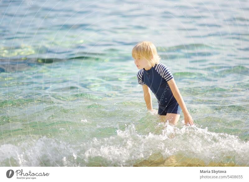 Niedlicher Junge im Teenageralter badet im Meer. Spaß Strandurlaub für Kinder. Sommerurlaub für Kinder. uv Schutz Badebekleidung Kleidung MEER Sonne spielen