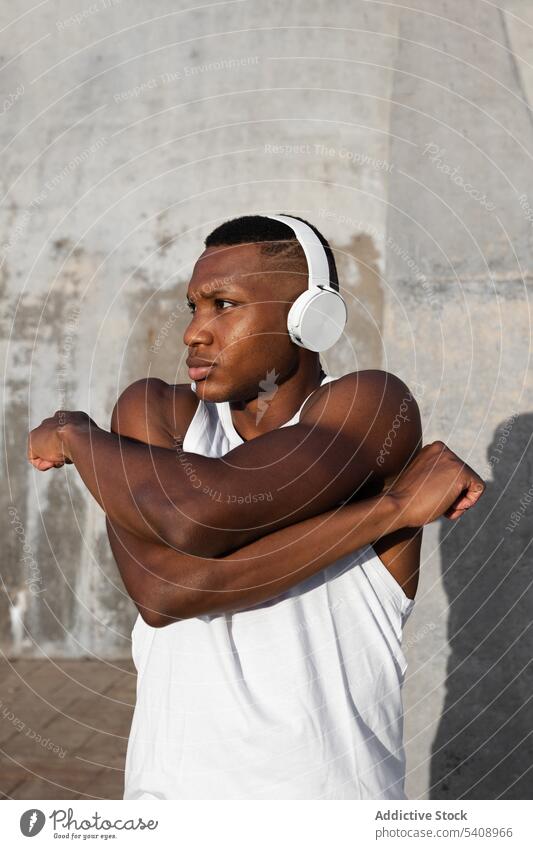 Schwarzer Läufer streckt seinen Nacken vor dem Training auf der Straße Mann Aufwärmen Dehnung Konzentration Übung Fitness Athlet Kopfhörer Energie männlich