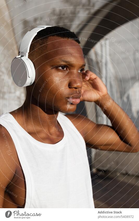 Schwarzer ernster Mann, der mit Kopfhörern Musik hört sich[Akk] entspannen Gesang Athlet zuhören Drahtlos Klang männlich ruhen Audio Melodie Wellness