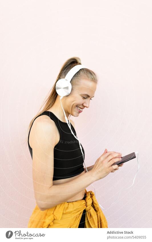 Junge Frau, die am Telefon Musik hört, isoliert auf hellem Hintergrund jung Jogger hören Kopfhörer Athlet Läufer rennen Sport Gesundheit passen Fitness