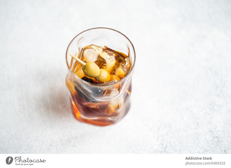 Cocktailglas mit Eis und Whiskey alkoholisches Getränk mit Stange von Oliven Alkohol Glas Schnaps trinken oliv liquide Portion dienen Würfel Glaswaren Kristalle