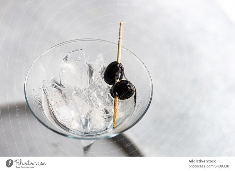 Martini-Cocktail mit schwarzen Oliven auf dem Tisch Alkohol Getränk trinken schwarze Oliven Aperitif Glas Geschmack Schnaps köstlich Erfrischung Saum
