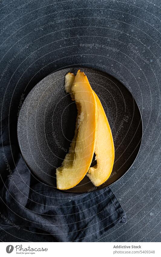 Scheiben von süßer gerissener Melone auf schwarzem Betontisch serviert Melonen Frucht Spielfigur dienen Teller lecker rustikal Tisch Sommer Vitamin Gesundheit