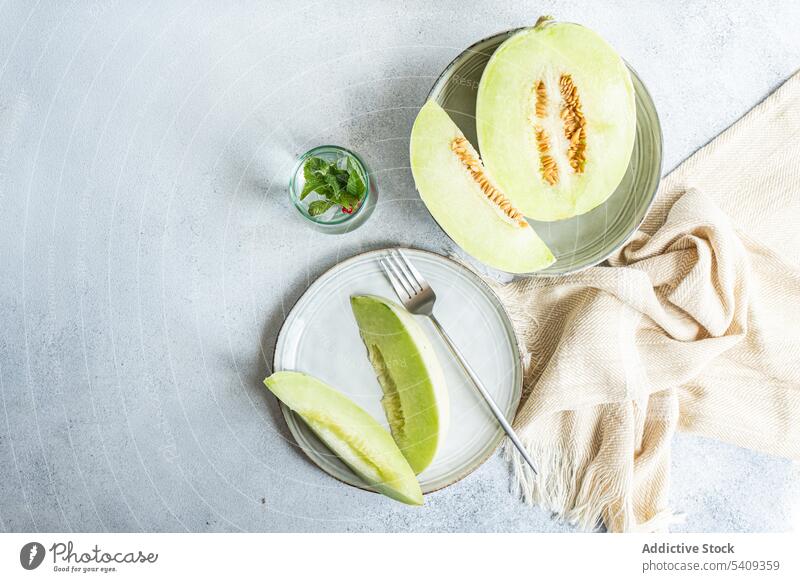 Honigtau grüne Sorte von Melone Obst zum Nachtisch Stillleben Melonen Hintergrund Teile unreif groß Frucht trinken weiß Keramik Teller Licht farbig Glas Tisch