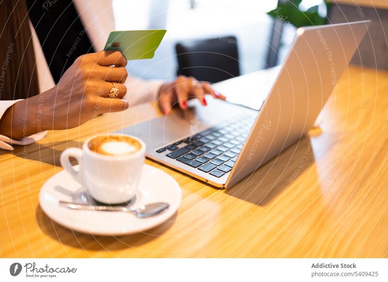 Unbekannte Frau beim Online-Einkauf Geschäftsfrau online kaufen Kauf Kreditkarte e-Commerce Laptop Büro benutzend Kaffee ethnisch Tasse jung Afroamerikaner