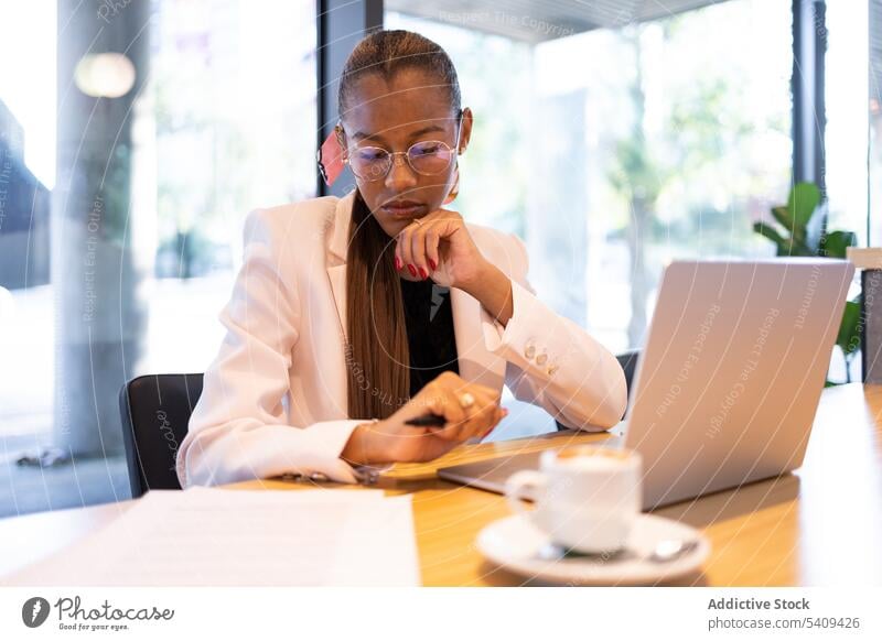 Konzentrierte Frau erledigt Papierkram im Büro Geschäftsfrau Konzentration Fokus Laptop Arbeit Kaffee beschäftigt Unternehmer Tisch Arbeitsplatz Tasse
