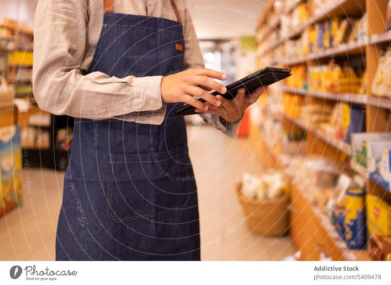 Anonymer Mann mit Tablet, der in einem Lebensmittelgeschäft Waren kontrolliert Werkstatt Tablette Supermarkt Bestandsaufnahme Kontrolle prüfen Apparatur Laden