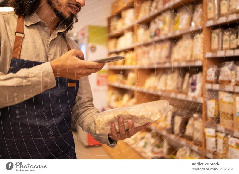 Crop Black Verkäufer Scannen Code Lebensmittel im Lebensmittelgeschäft Mann Laden Barcode Werkstatt Regal Smartphone Mitarbeiter Paket Arbeiter Supermarkt