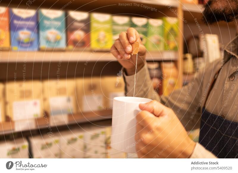 Anonymer Mann trinkt heißen Tee in einem Becher Tasse Kaffee Laden trinken Arbeiter Heißgetränk Werkstatt männlich Wahl Mitarbeiter modern Kauf Getränk Regal