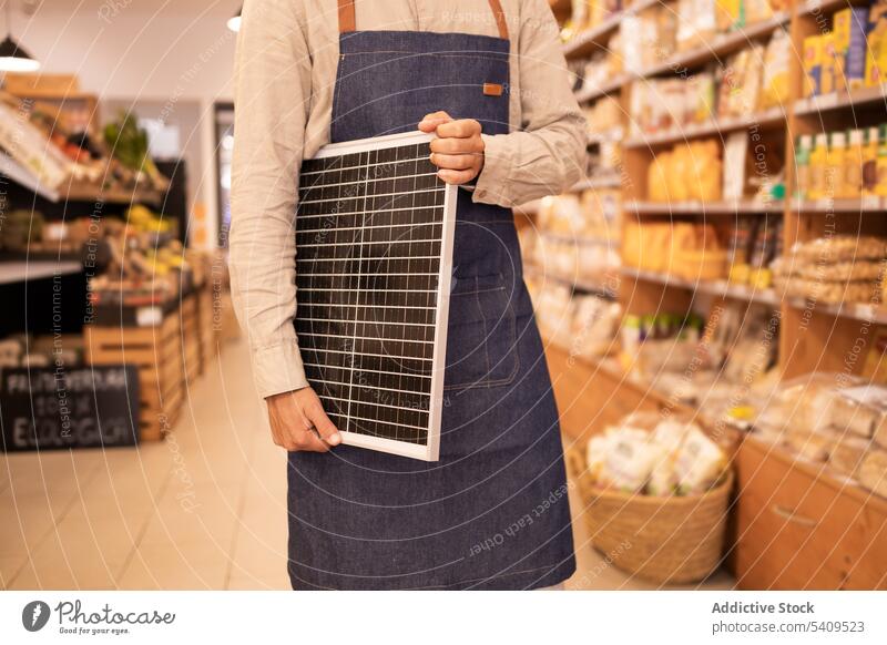 Anonymer Ernteverkäufer mit tragbarem Solarpanel im Laden Mann Supermarkt Werkstatt solar Panel Arbeiter Verkäufer Kauf modern Gerät Käufer Energie Generation