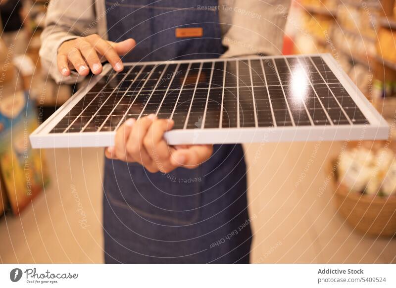 Anonymer Ernteverkäufer mit tragbarem Solarpanel im Laden Mann Supermarkt Werkstatt solar Panel Arbeiter Verkäufer Kauf modern Gerät Käufer Energie Generation