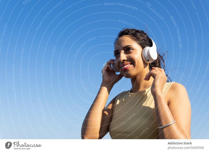 Indische Frau mit Kopfhörern zuhören Lächeln Glück Musik benutzend ruhen Sommer Gesang Inder jung sich[Akk] entspannen Melodie Drahtlos Felsen meloman Audio