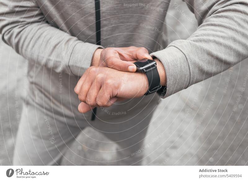 Unbekannter Mann in Sportkleidung steht und prüft die Zeit auf seiner Smartwatch prüfen intelligente Uhr Asphalt Straße Athlet punktuell Zeitplan Sommer