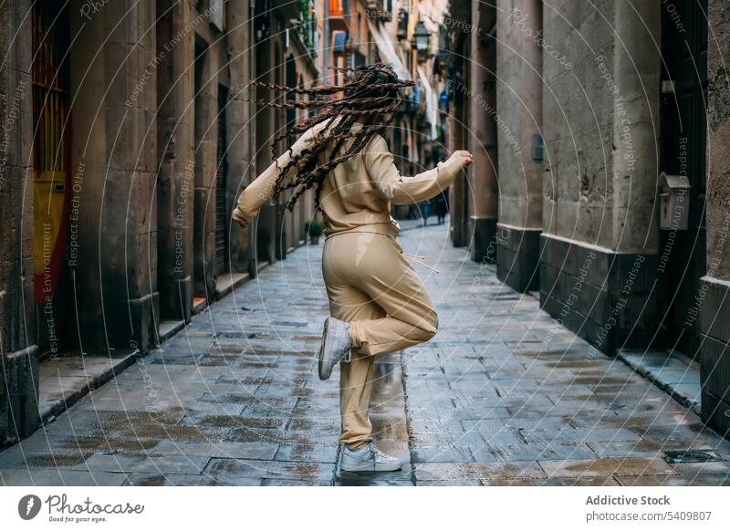 Unbekannte Frau tanzt auf der Straße Tanzen Outfit Stil Architektur Straßenbelag eng Stadt aktiv Gebäude Wand tagsüber lässig Großstadt cool Turnschuh Geflecht