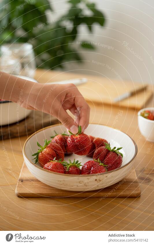 Crop-Frau hält Erdbeere in Schale über Holztisch Person nehmen Erdbeeren reif Lebensmittel frisch Marmelade süß vorbereiten Frucht geschmackvoll lecker Vitamin