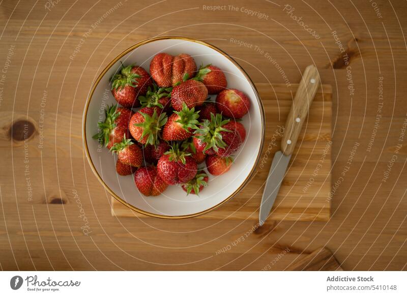 Teller mit reifen Erdbeeren und Messer auf Holztisch Schalen & Schüsseln Beeren frisch lecker Lebensmittel Tisch gesunde Ernährung Holzplatte Vitamin