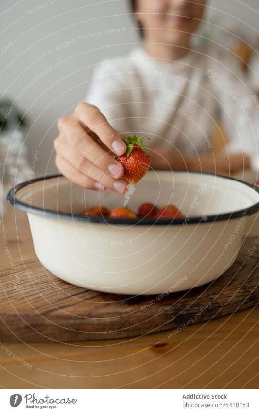 Crop-Frau pflückt Erdbeeren aus einer Schale über dem Tisch Schalen & Schüsseln Hand lecker Beeren Frucht frisch gesunde Ernährung Lebensmittel Café süß