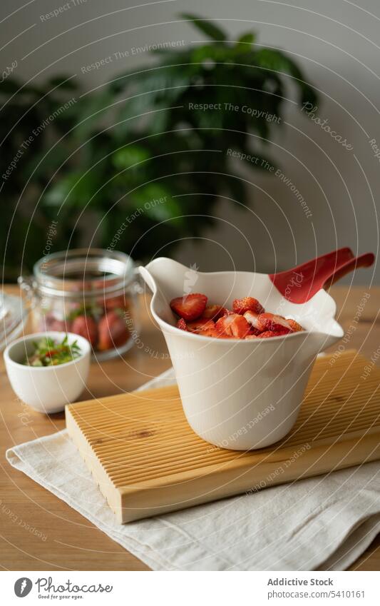 In Scheiben geschnittene Erdbeeren in einer Schale auf dem Tisch Schalen & Schüsseln Marmelade süß lecker Lebensmittel Beeren Dessert frisch Küche hölzern