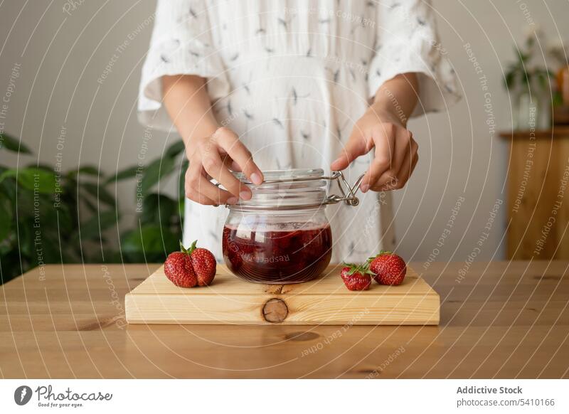 Crop-Frau mit Erdbeermarmelade auf Holztisch Erdbeeren Glas geschmackvoll lecker Marmelade Tisch Küche hölzern Frühstück Beeren Gesundheit frisch lässig süß