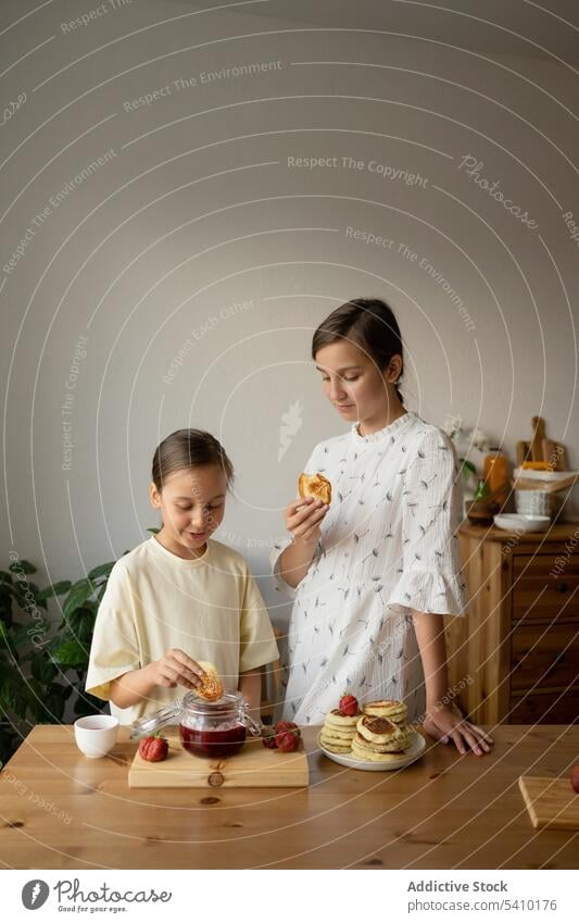 Positive Schwestern beim süßen Frühstück Mädchen Erdbeeren essen Küche Lebensmittel Zusammensein Pfannkuchen Marmelade positiv Morgen Geschwisterkind Familie