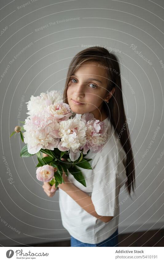 Ruhig preteen Mädchen Kind stehend mit blühenden Pfingstrose Blume mit Stiel verträumt Blütezeit sanft Porträt filigran Angebot Kindheit geblümt charmant