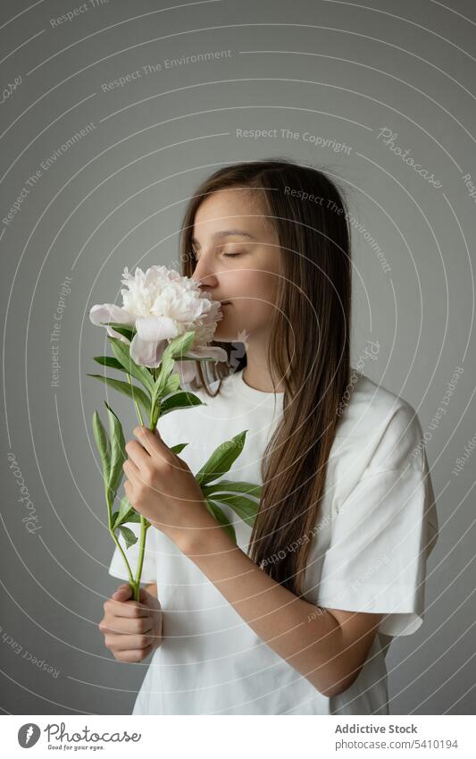 Calm preteen Mädchen Kind stehend mit geschlossenen Augen mit blühenden Pfingstrose Blume mit Stiel verträumt Augen geschlossen Blütezeit sanft Porträt filigran