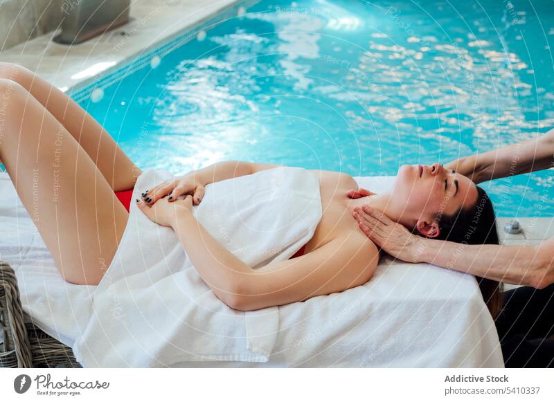 Junge Frau auf dem Bett liegend während einer Gesichtsmassagetherapie Spa Massage Handtuch Therapie Masseurin Pool Schulter Verfahren Wellness Schönheit Lügen