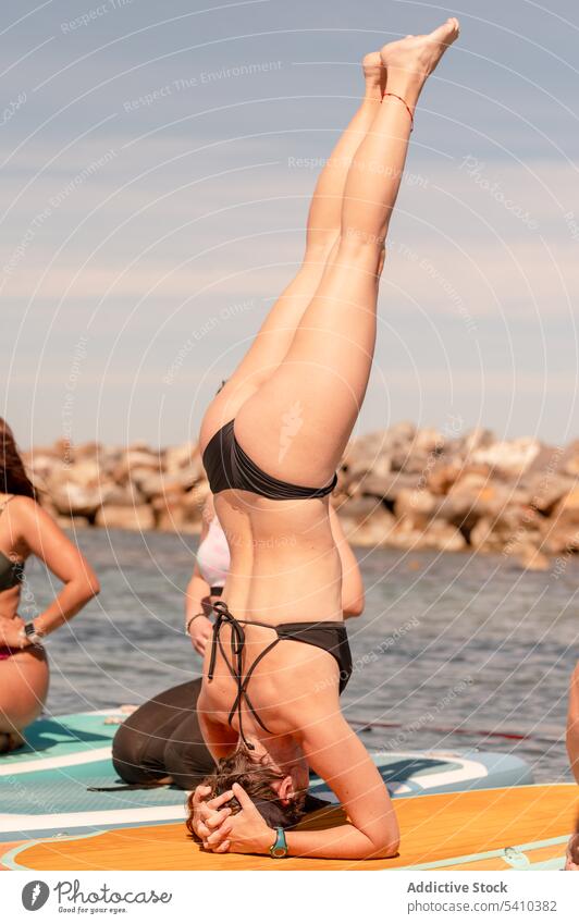 Frau im Bikini macht SUP-Yoga-Übung auf dem Paddleboard Kopfstand Paddelbrett Schwimmer Sup-Yoga ruhen ernst MEER Erholung Wasser Sommer Resort Meer