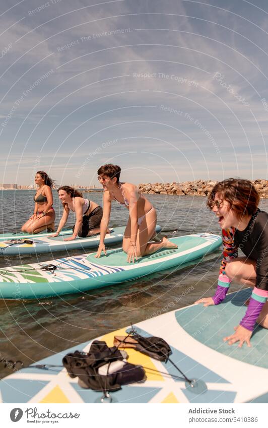 Fröhliche Frauen in Kuh-Yoga-Pose auf Paddleboards auf dem Meer Paddelbrett Überraschung Glück MEER üben heiter Badebekleidung Badeanzug Bikini Wasser Sommer
