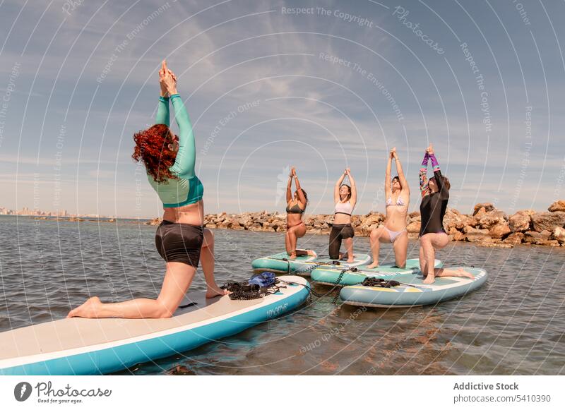 Gruppe von Frauen, die Yoga in der Haltung des Kriegers 1 machen Strand Dehnung üben Gleichgewicht Krieger-Pose Übung Aktivität Küste knien positionieren