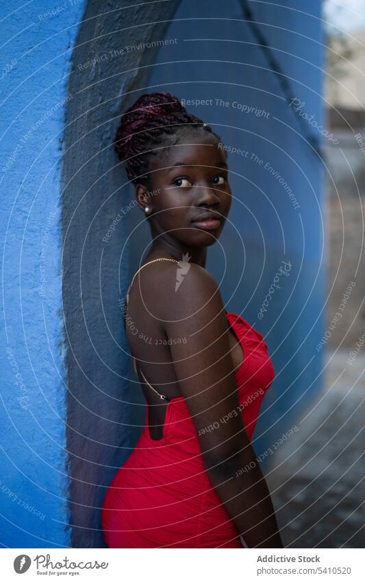 Afroamerikanische Frau im roten Kleid nachdenklich besinnlich Wand Stil trendy Mode Outfit Denken fettarm Windstille verträumt stehen Persönlichkeit Zopf